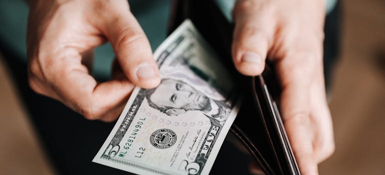 person putting dollar bill in wallet