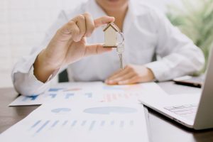 a woman in a white long sleeve shirt holding keys to a new home
