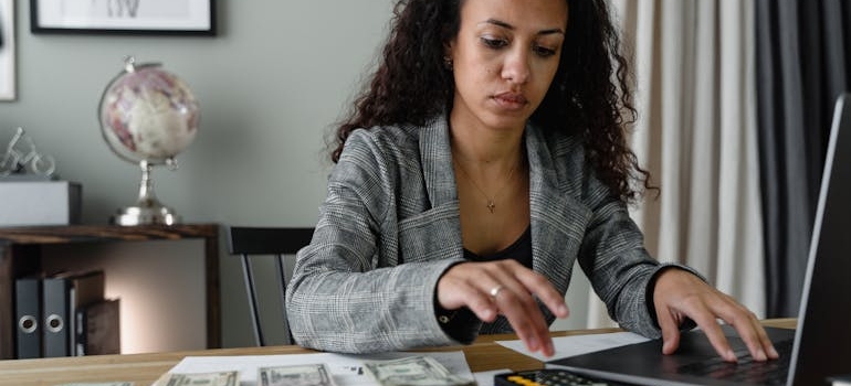 person calculating the cost of long distance moving with calculator and notebook