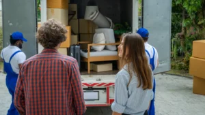 A happy couple watches their moving company load the truck so they can move into a new house.