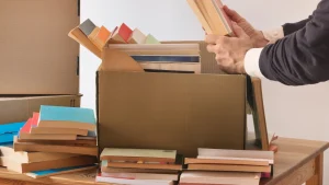 Man places old books into a box to be donated as part of their moving to-do list.