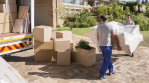Two men load a sofa into the back of a moving truck.